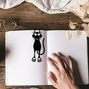 Creative black 3D cartoon cat bookmark shown hanging on a page in a vintage lifestyle setting