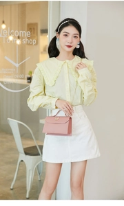 Pink faux leather handbag detail with elegant butterfly-shaped metal clasp and gold chain