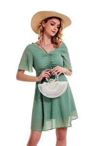Green polka dot dress detail with a stylish white hollow out bamboo summer beach bag