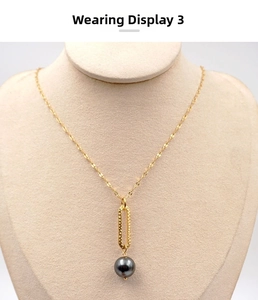 Detailed view of a gold textured oval pendant with a dark grey pearl on a wavy chain