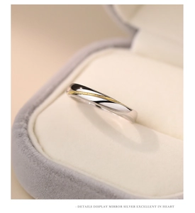 Detail of mirror silver ring with a frosted gold line accent on a soft grey velvet box