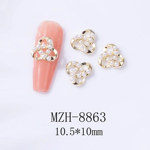 Gros plan de bijoux d'ongles trèfle doré de 10,5mm avec perles sur faux ongles roses