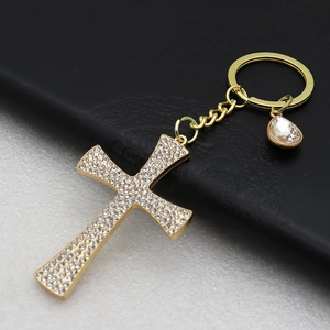 Detail of gold cross keychain featuring sparkling clear rhinestones on a textured surface