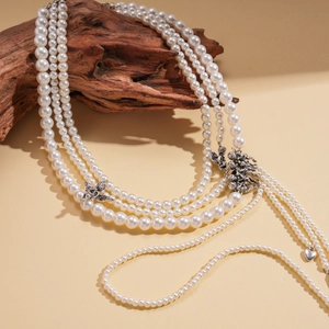 Macro detail of multi-layered pearl necklace with vintage silver angel and heart pendant