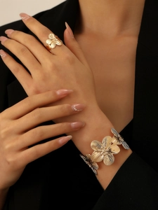 Detail of gold flower ring and bracelet set with textured petals on model's hand