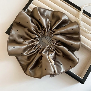 Détail d'un chouchou en satin imprimé léopard marron sur un plateau à bijoux avec perles