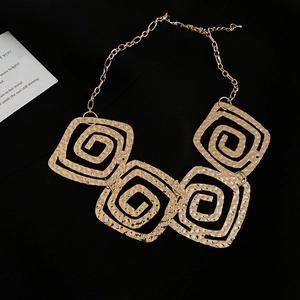 Macro shot of gold square pendant necklace featuring unique spiral texture on black background