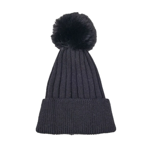 Close-up of black ribbed knit winter hat featuring a fluffy faux fur pompom detail