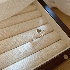 Close-up of vintage silver ring with oval green gemstone set in intricate hollow band