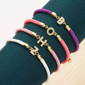 Letter charm woven bracelets with sparkling cubic zirconia on green display