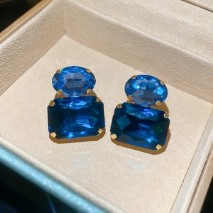 Close-up of royal blue faceted gems in gold claw setting on elegant earrings