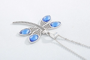 Detailed close-up of a dragonfly pendant with faceted blue crystals and silver chain