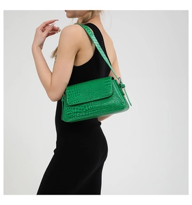Close-up of a green crocodile pattern underarm bag worn by a model in a professional side view