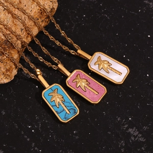 Detail of 18K gold plated tropical pendant necklaces with palm trees and colorful shell