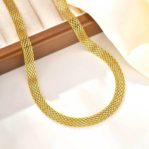 Detail view of a gold mesh chain necklace displayed on white silk and vintage wood