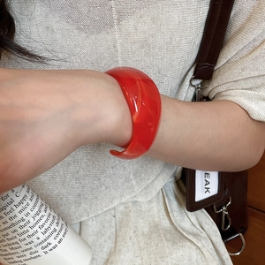 Macro shot of red acrylic C-shaped bracelet with marble texture worn on wrist