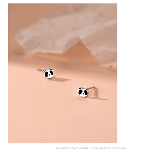 Makro-Detail von Sterling Silber Panda-Ohrsteckern auf minimalistisch rosa Hintergrund