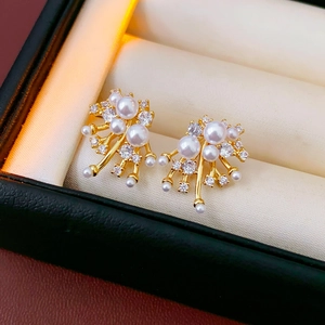 Detailed close-up of gold fireworks stud earrings with white pearls and zircons on padding