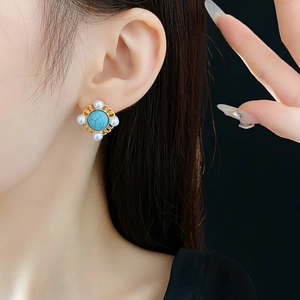 Close-up of vintage earrings featuring turquoise center stones and pearl accents