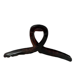 Deep brown tortoiseshell acetate hair claw clip with ribbon bow design on white background