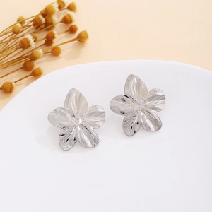 Silver flower stud earrings with pleated petals and beaded center on display tray