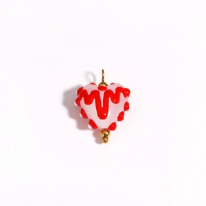 Macro detail of heart-shaped glass bead with pink base and red wavy patterns