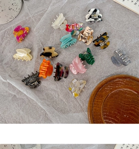 Detailed top view of various colorful mini acetate hair claws on a textured grey background