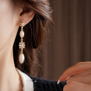 Macro side view of vintage tassel earrings with pearls and zircons worn by a model