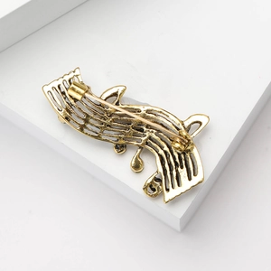 Detailed view of the golden musical note brooch back showing a secure pin closure