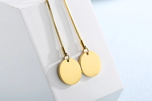Detailed view of long gold snake chain earrings with circular pendants on display