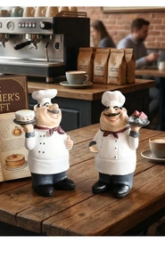 Detail of chef figurines holding a cake and fruit tray on a rustic wooden cafe table