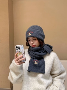 Detailed view of dark grey knit hat and scarf set featuring yellow puppy embroidery