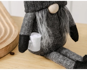 Close-up of a Nordic Christmas gnome with grey felt hat holding a mini roll paper accessory