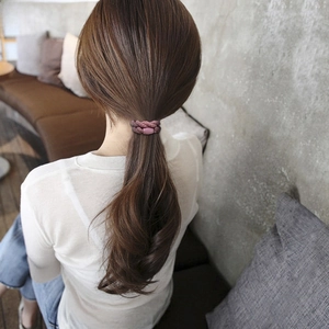 Detail of pink woven hair tie with a cylinder bead worn on a ponytail in daily life