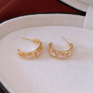 Detailed close-up of gold-plated heart-shaped earrings with pink enamel in a white jewelry box