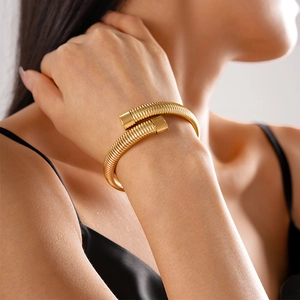 Detailed view of a golden flexible snake-style open bracelet in Tubogas design worn by a model