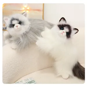Close-up of fluffy grey and black ragdoll cat plush toys on a soft white sofa