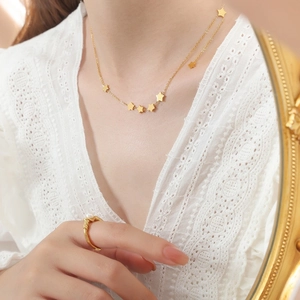Elegant gold titanium star necklace with delicate charms on female model with lace outfit