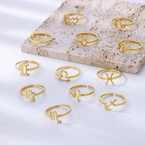 Adjustable gold zodiac rings with hollowed constellation symbols on travertine stone display