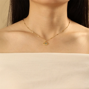 Close-up of golden evil eye pendant necklace worn by a model on collarbone