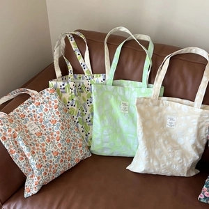 Detail view of four printed cotton tote bags with floral and geometric patterns