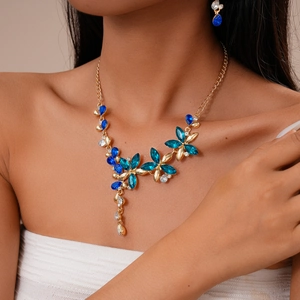 Détail du collier à fleurs dorées avec strass bleus porté sur le cou d'un mannequin