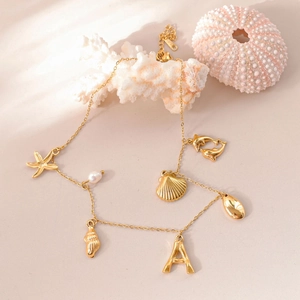 Detail of 18k gold ocean-themed necklace with pearl, starfish, and letter A charms