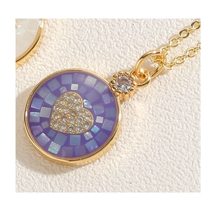 Vue macro du pendentif cœur doré avec détails en mosaïque violette et pierre zircon