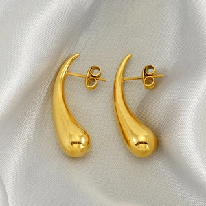 Polished gold teardrop earrings for women on silver silk background, vintage style jewelry
