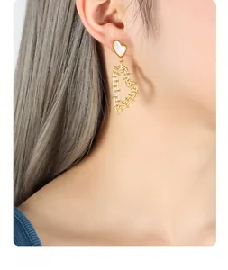 Close-up of gold woven heart earrings with mother of pearl inlay on model ear