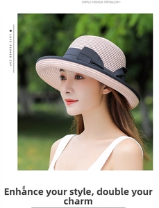 Detail of a beige straw sun hat with a black ribbon bow and elegant wavy brim texture