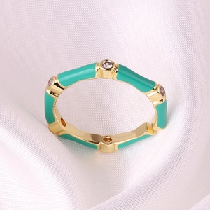 Macro detail of gold bamboo ring with teal enamel glaze and small sparkling zircons