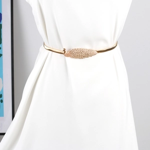 Detail der goldenen Pfau-Schnalle elastischer Metallgürtel mit Strass auf weißem Kleid