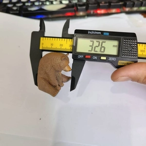Detail showing a cute brown bear resin figurine being measured with a digital caliper